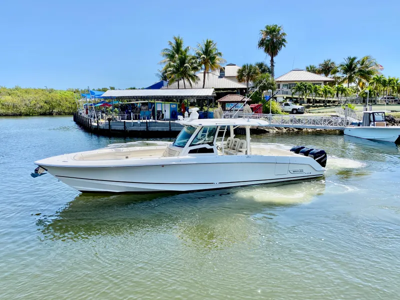 Slide: The Image of 2019 Boston Whaler 380 Outrage cruising near a tropical waterfront with palm trees. - 28