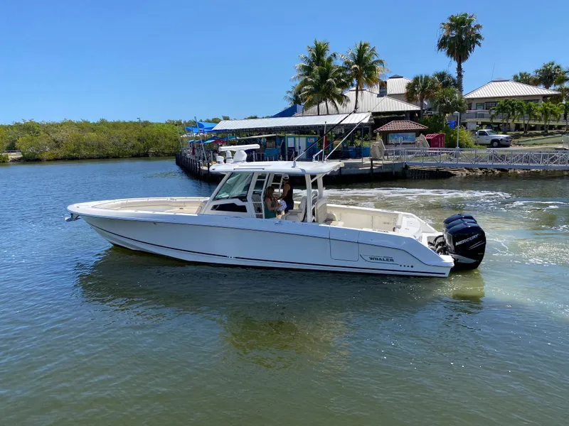 Slide: The Image of 2019 Boston Whaler 380 Outrage boat cruising near a tropical waterfront. - 8