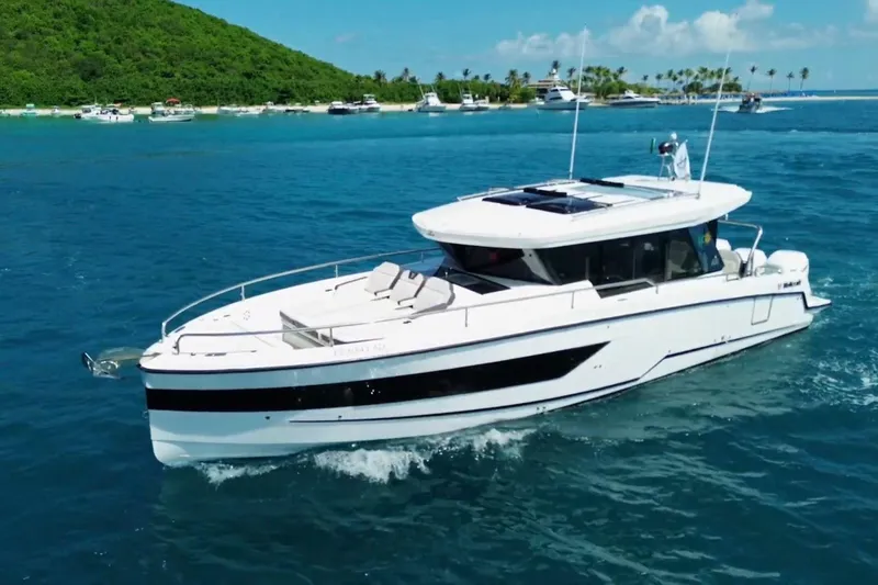 The Image of 2023 Wellcraft 355 boat cruising in clear blue waters near a tropical island. - 0