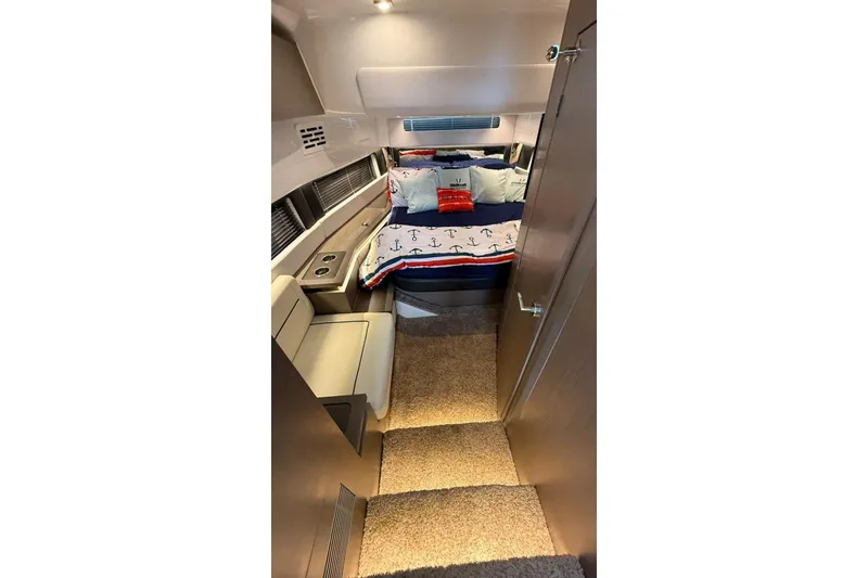 Slide: The Image of 2023 Wellcraft 355 cabin interior with nautical-themed bedding and modern seating. - 14