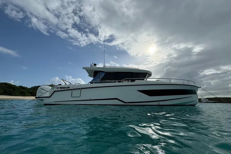Slide: The Image of 2023 Wellcraft 355 boat anchored in clear blue water under a cloudy sky. - 23