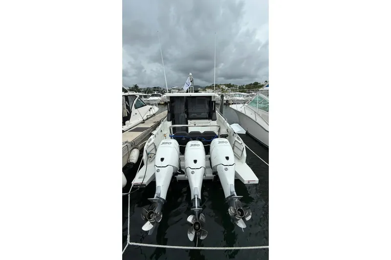 Slide: The Image of 2023 Wellcraft 355 boat with triple outboard engines docked under cloudy skies. - 4
