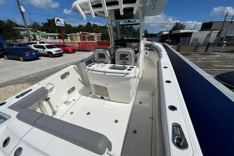 Slide: The Image of 2024 Boston Whaler 280 Outrage boat interior, featuring seating and console, parked outdoors. - 5
