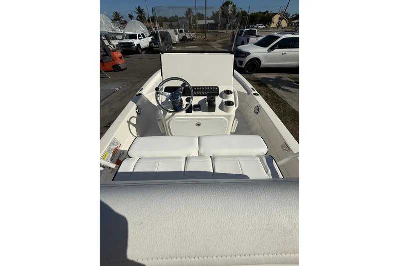 Slide: The Image of 2025 Skeeter SX221 boat interior with steering wheel and seating, parked outdoors. - 10