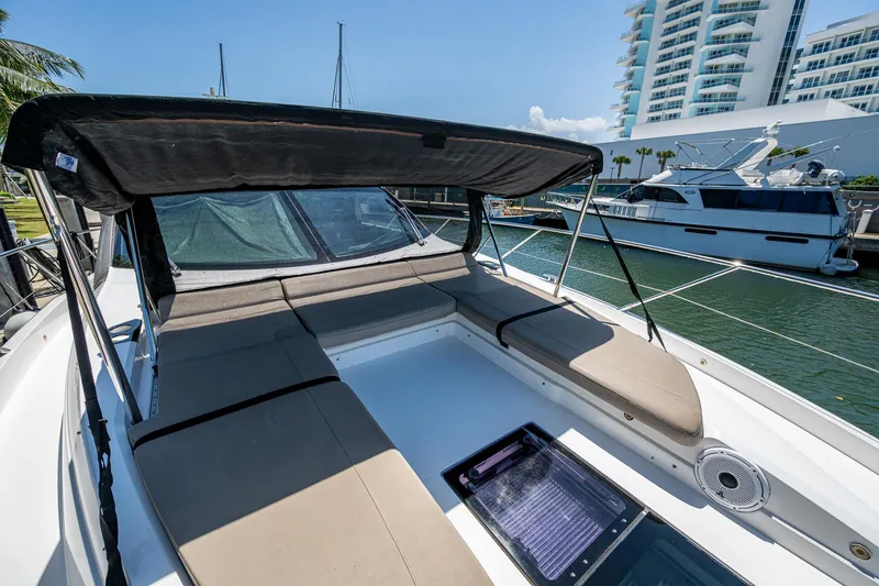 Slide: The Image of 2019 Sunseeker Predator 50 yacht with sunbathing area, docked near modern buildings. - 14