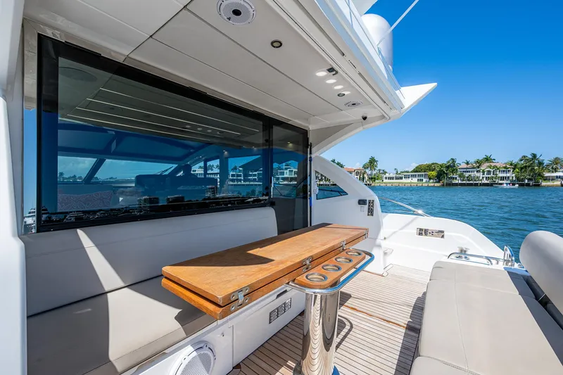 Slide: The Image of 2019 Sunseeker Predator 50 yacht deck with seating and table, overlooking water and shoreline. - 19