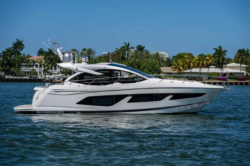 Slide: The Image of 2019 Sunseeker Predator 50 yacht cruising on a sunny day, surrounded by palm trees. - 5