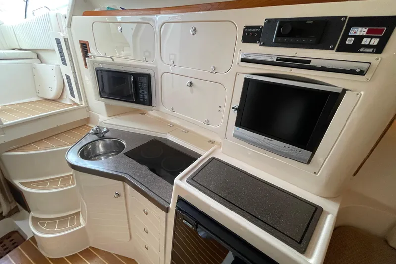 Slide: The Image of 2007 Grady-White Express 330 boat interior with kitchenette, sink, microwave, and TV. - 31