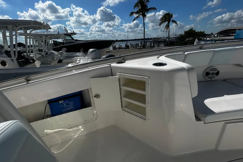 Slide: The Image of 2018 Robalo R302 Center Console boat interior with seating and storage, docked under a blue sky. - 7