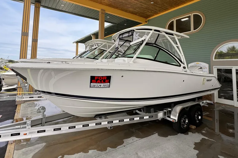 Slide: The Image of 2024 Pursuit DC 246 Dual Console boat for sale on trailer, displayed outdoors. - 0