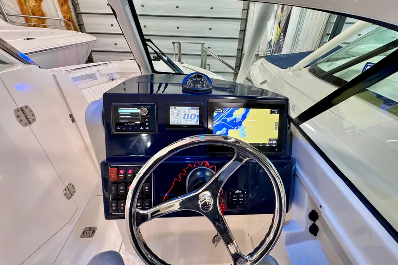 Slide: The Image of 2024 Pursuit DC 246 Dual Console boat dashboard with navigation screens and steering wheel. - 16