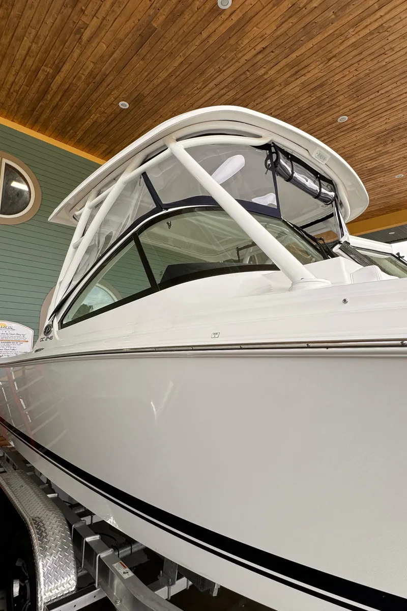 Slide: The Image of 2024 Pursuit DC 246 Dual Console boat with sleek design, displayed indoors. - 2