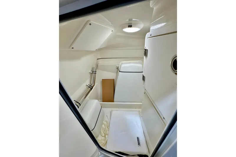 Slide: The Image of 2024 Pursuit DC 246 Dual Console interior cabin with white finish and storage compartments. - 22
