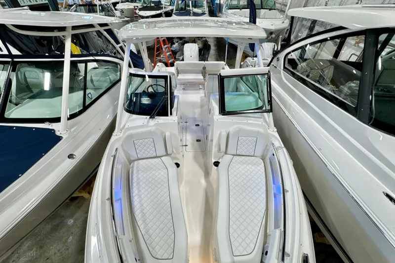 Slide: The Image of 2024 Pursuit DC 246 Dual Console boat in showroom, featuring spacious seating and modern design. - 24