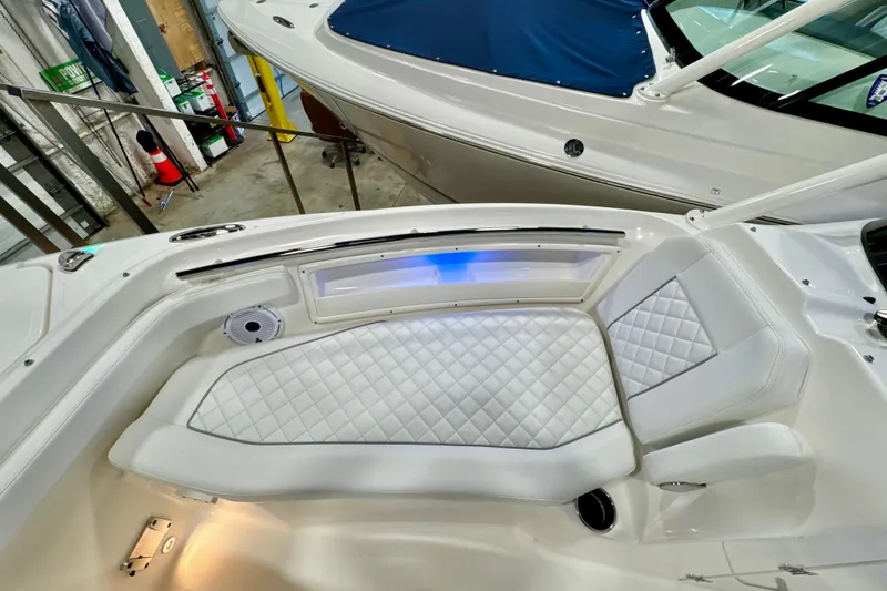 Slide: The Image of 2024 Pursuit DC 246 Dual Console boat interior with white quilted seating and ambient lighting. - 26