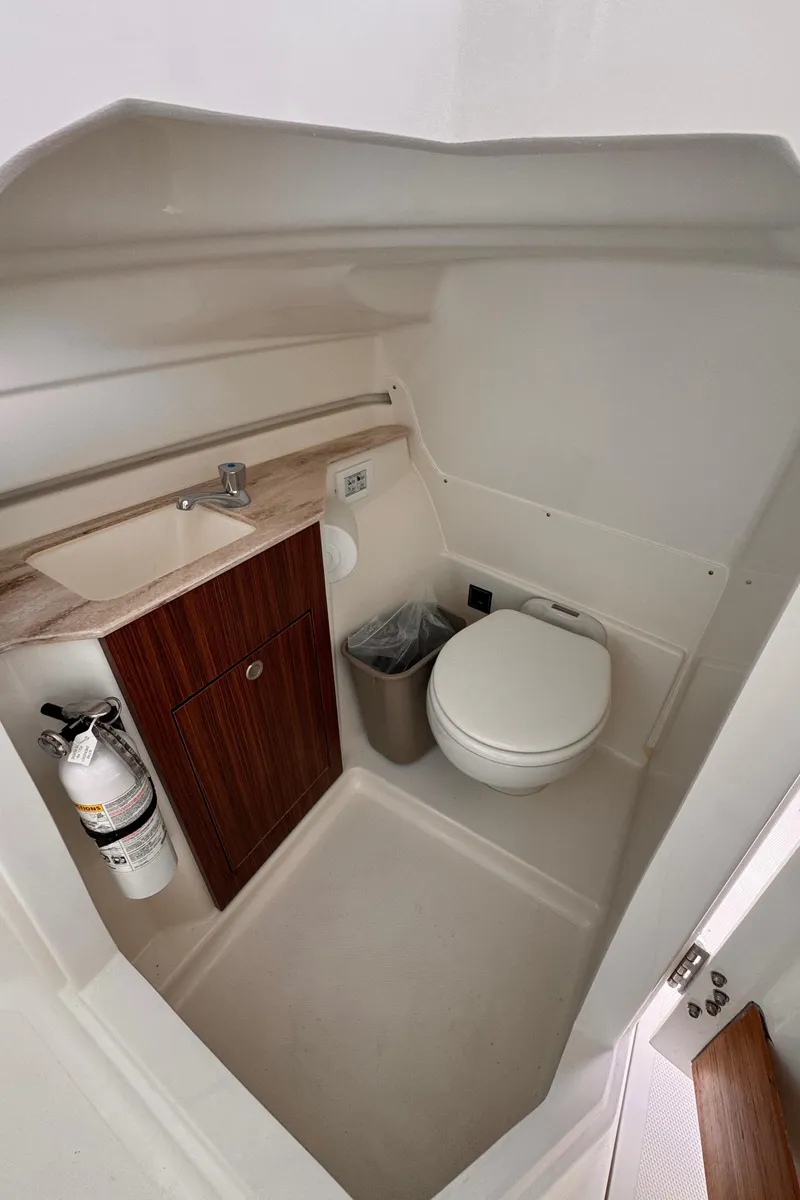 Slide: The Image of 2024 Pursuit DC 246 Dual Console boat bathroom with sink, toilet, and fire extinguisher. - 37