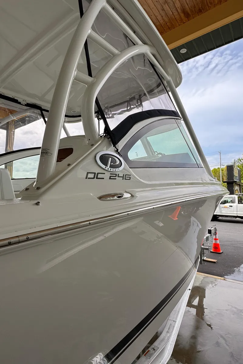 Slide: The Image of 2024 Pursuit DC 246 Dual Console boat, sleek design, docked under shelter. - 43