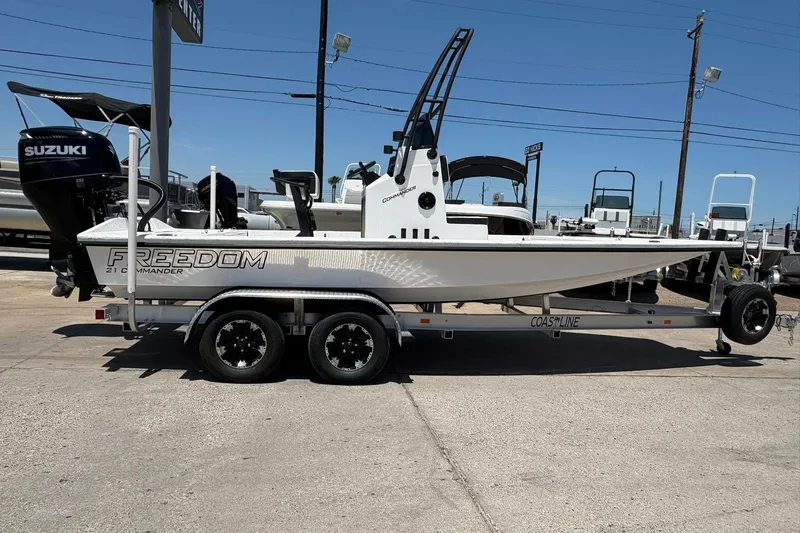 Slide: The Image of 2026 Freedom Boats 21' Commander on trailer, displayed outdoors with Suzuki engine. - 16