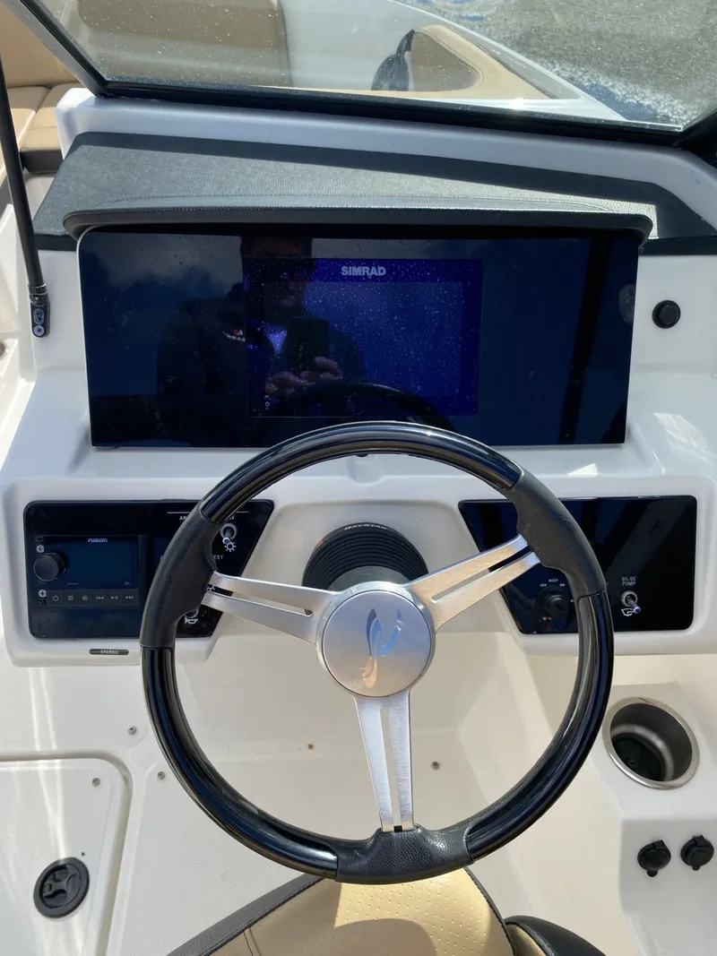 Slide: The Image of 2023 Sea Ray SPX 210 boat dashboard with steering wheel and navigation display. - 2