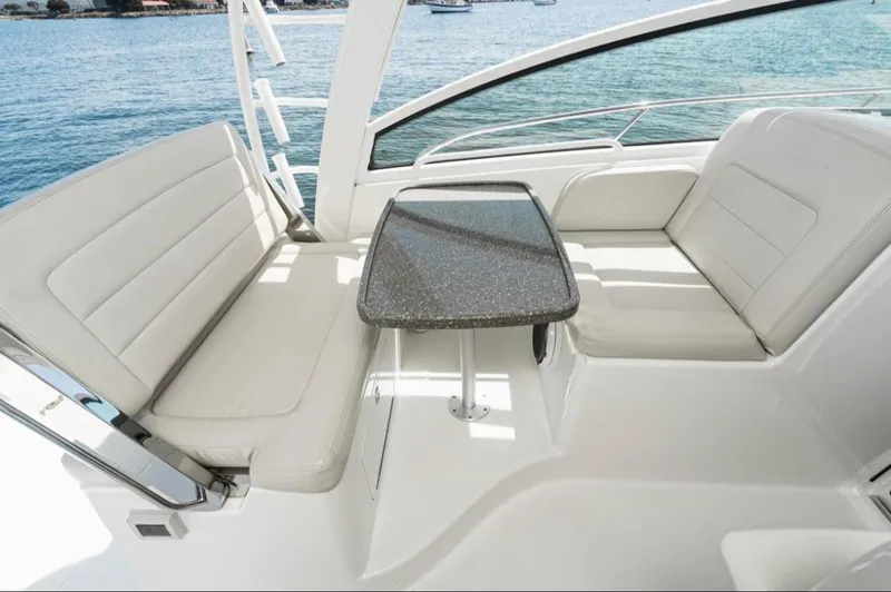 Slide: The Image of 2019 Boston Whaler 345 Conquest interior with cushioned seating and table, overlooking the ocean. - 13