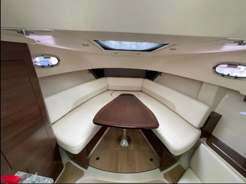 Slide: The Image of 2019 Boston Whaler 345 Conquest cabin interior with plush seating and wooden table. - 18