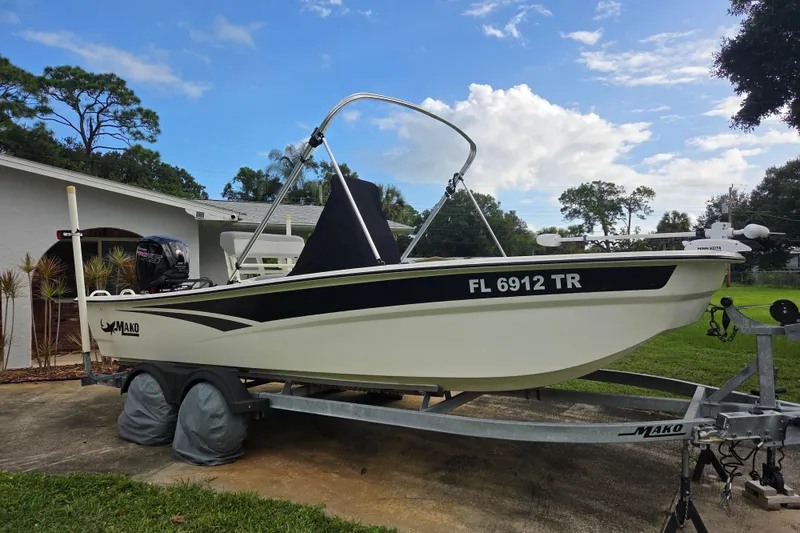 Slide: The Image of 2023 Mako Pro Skiff 19 CC boat on trailer, parked outdoors under a blue sky. - 1