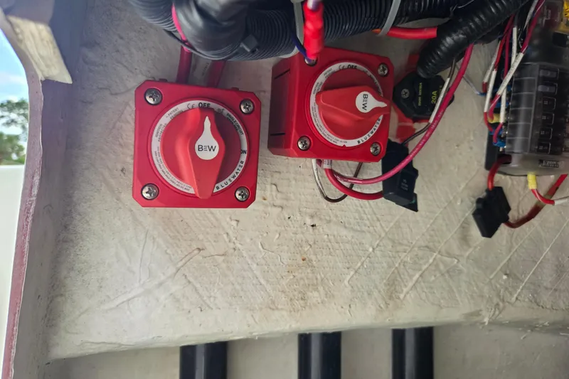 Slide: The Image of Red battery switches and wiring inside a 2023 Mako Pro Skiff 19 CC boat. - 27
