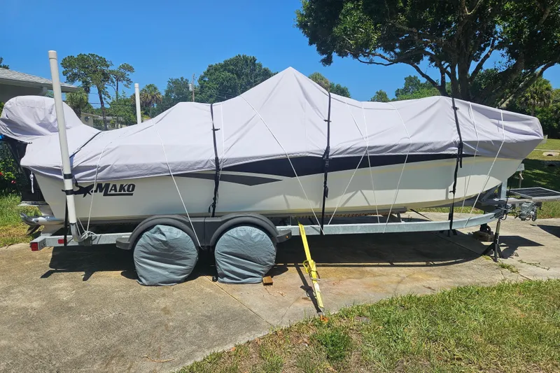 Slide: The Image of 2023 Mako Pro Skiff 19 CC boat covered on trailer, parked outdoors. - 8