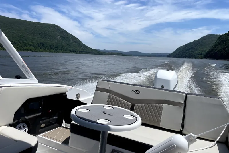 Slide: The Image of 2023 Monterey 275SS Super Sport boat cruising on a scenic lake with lush green hills. - 3