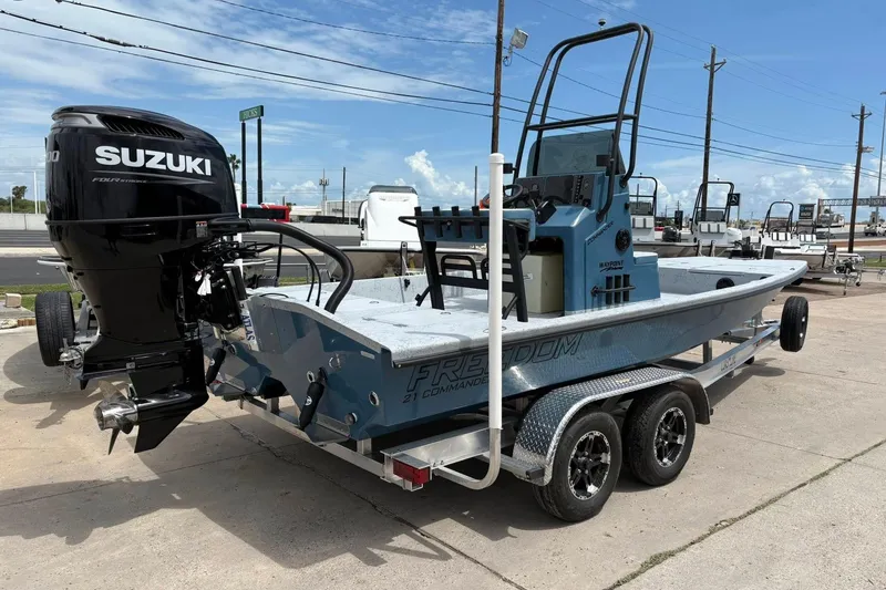 Slide: The Image of 2026 Freedom Boats 21' Commander with Suzuki engine on trailer, parked outdoors. - 17