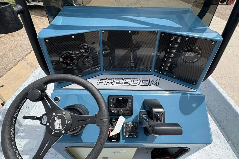 Slide: The Image of 2026 Freedom Boats 21' Commander dashboard with steering wheel and control panel. - 5
