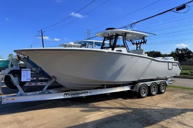 The Image of 2026 Tidewater 302 CC Adventure boat on a triple-axle trailer under clear blue sky. - 1