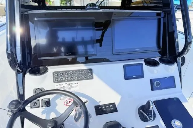 Slide: The Image of 2026 Tidewater 302 CC Adventure boat dashboard with dual screens and steering wheel. - 11