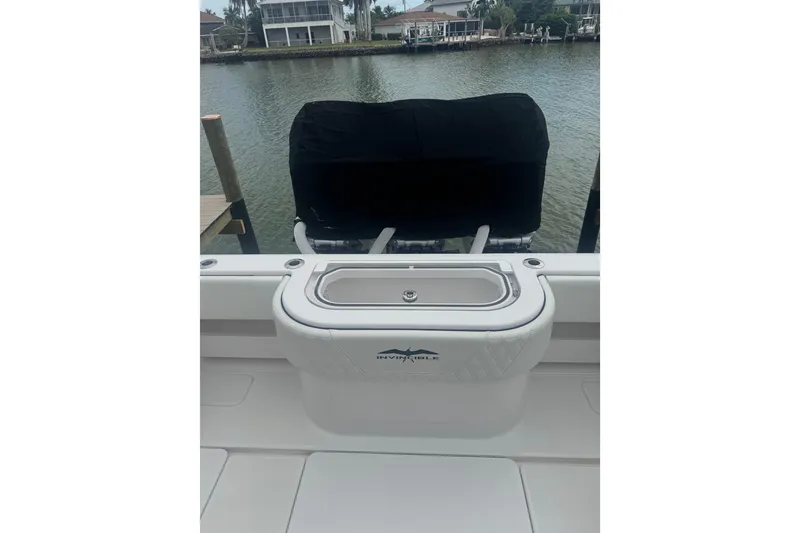 Slide: The Image of 2024 Invincible 39 Open Fisherman boat with covered engine, docked by waterfront homes. - 13