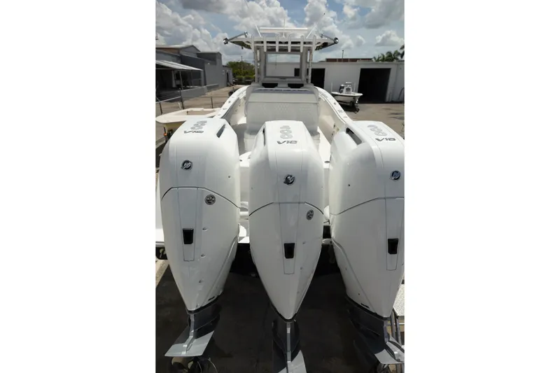 Slide: The Image of 2024 Invincible 39 Open Fisherman boat with triple outboard engines, docked under a cloudy sky. - 44