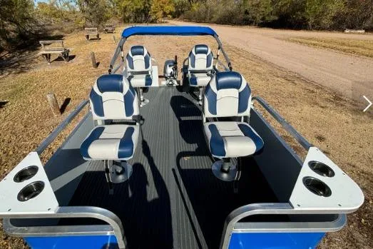 Slide: The Image of 2025 Pond-Tini Series 12 boat with blue and white seating, parked on a dirt path. - 6