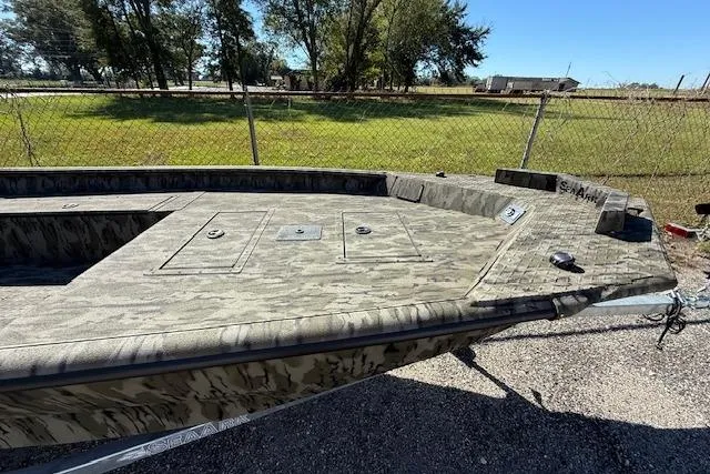 Slide: The Image of 2025 SeaArk 1752 Slayer Pro boat with camouflage design, parked outdoors. - 2