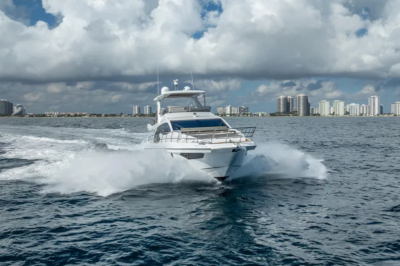 Slide: The Image of 2019 Azimut 66 yacht cruising on open water with city skyline backdrop. - 12