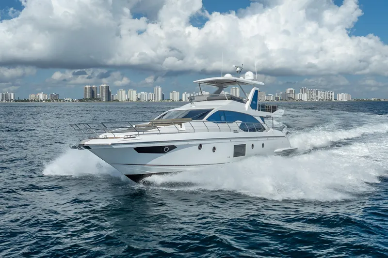 Slide: The Image of 2019 Azimut 66 yacht cruising on open water with city skyline backdrop. - 14
