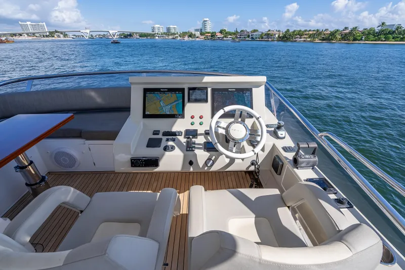 Slide: The Image of 2019 Azimut 66 yacht helm with navigation screens, steering wheel, and ocean view. - 48