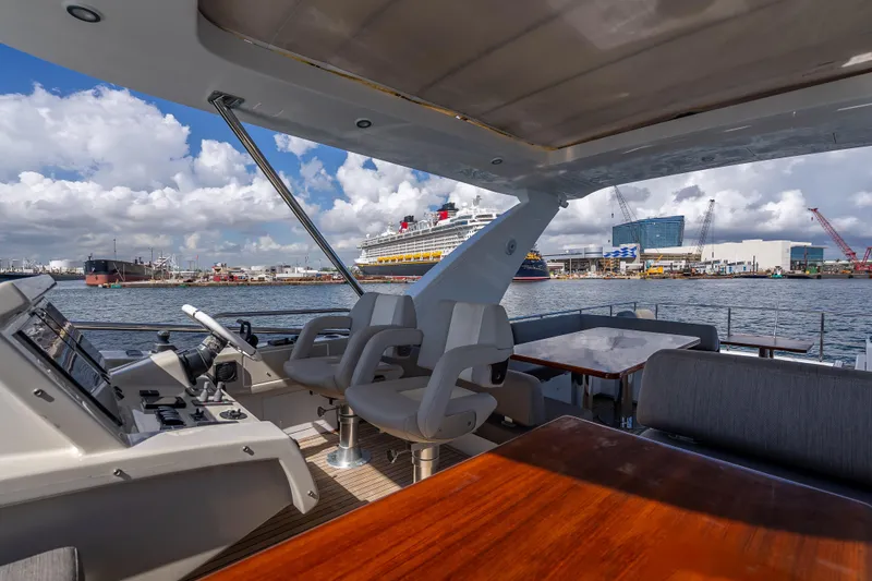 Slide: The Image of 2019 Azimut 66 yacht interior with harbor view, featuring modern seating and navigation controls. - 49