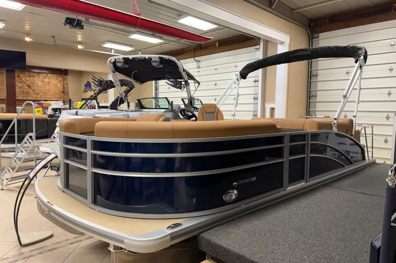 The Image of 2026 Harris Cruiser 190 pontoon boat in showroom, featuring tan seating and sleek design. - 1