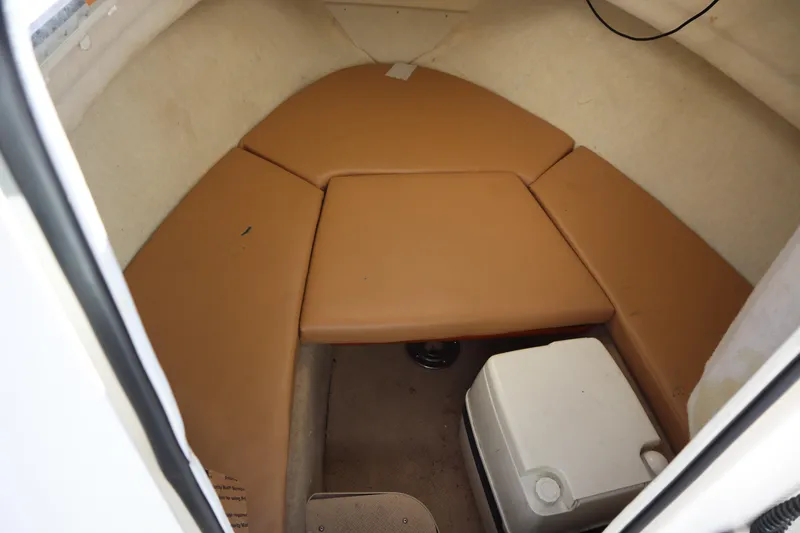 Slide: The Image of 2008 Trophy 2102 Walkaround cabin interior with tan cushions and a cooler. - 6