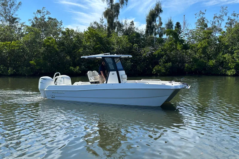 The Image of 2026 World Cat 235 TE boat cruising on a calm river, surrounded by lush greenery. - 0