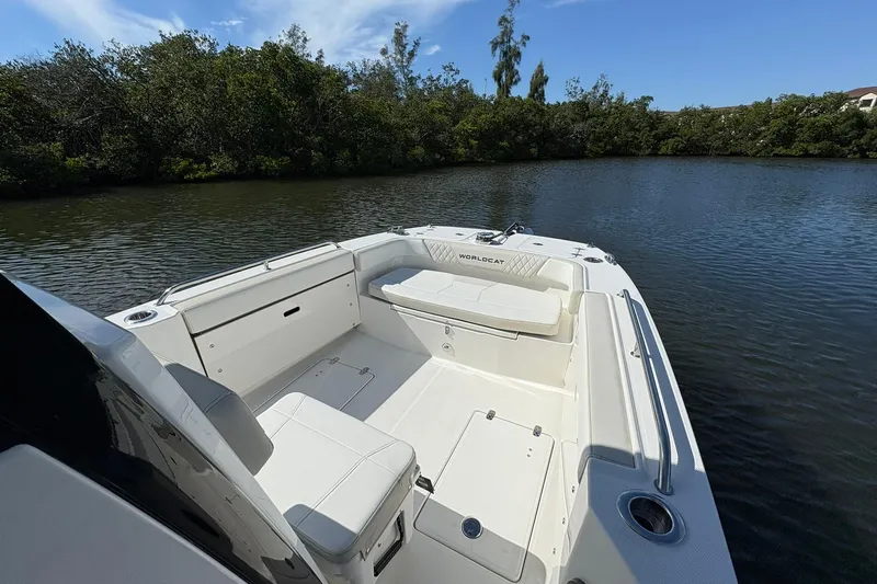 Slide: The Image of 2026 World Cat 235 TE boat interior with seating, on calm water, surrounded by trees. - 16