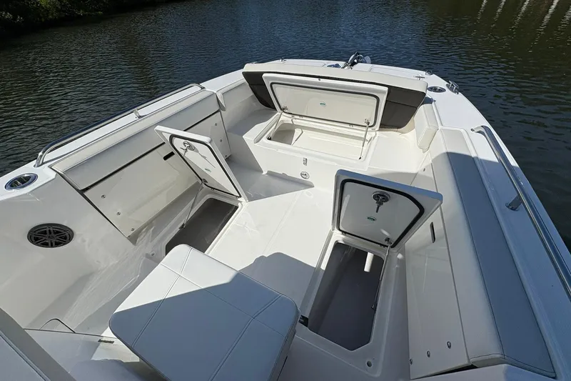 Slide: The Image of 2026 World Cat 235 TE boat interior with open storage compartments on calm water. - 19
