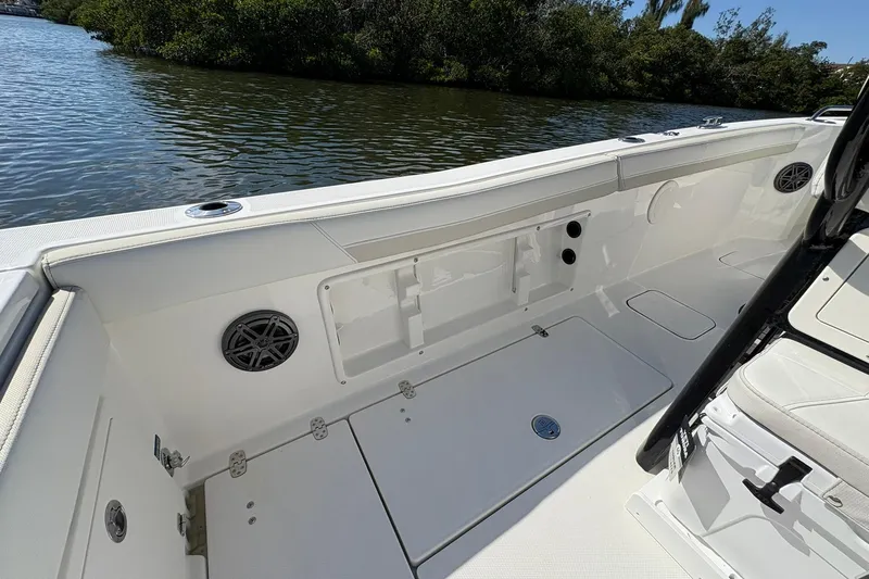 Slide: The Image of 2026 World Cat 235 TE boat interior with seating and storage, near lush waterway. - 22