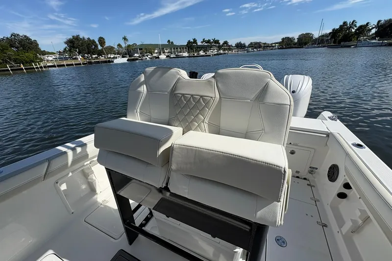 Slide: The Image of 2026 World Cat 235 TE boat interior with white seating, docked on a calm waterway. - 24