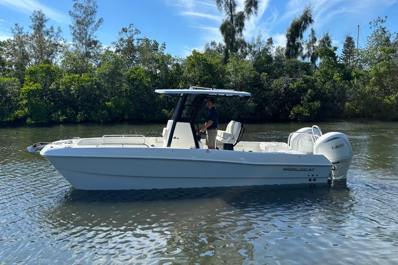 Slide: The Image of 2026 World Cat 235 TE boat on calm water, surrounded by lush greenery. - 5