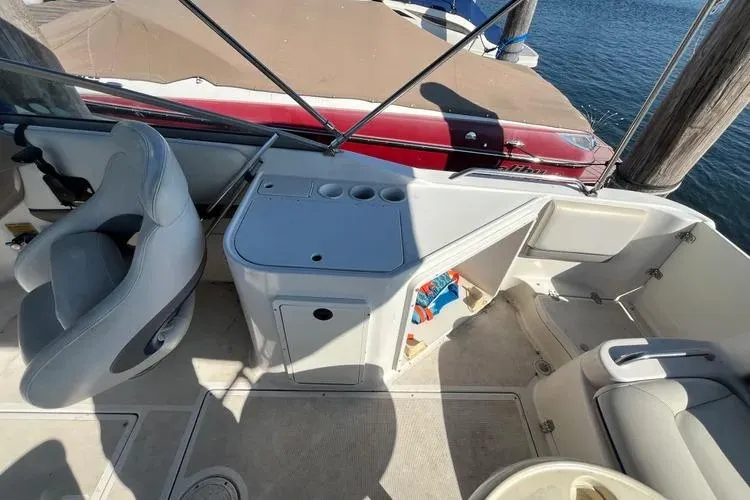 Slide: The Image of 2002 Four Winns 264 Funship interior with seating and storage, docked by the water. - 12